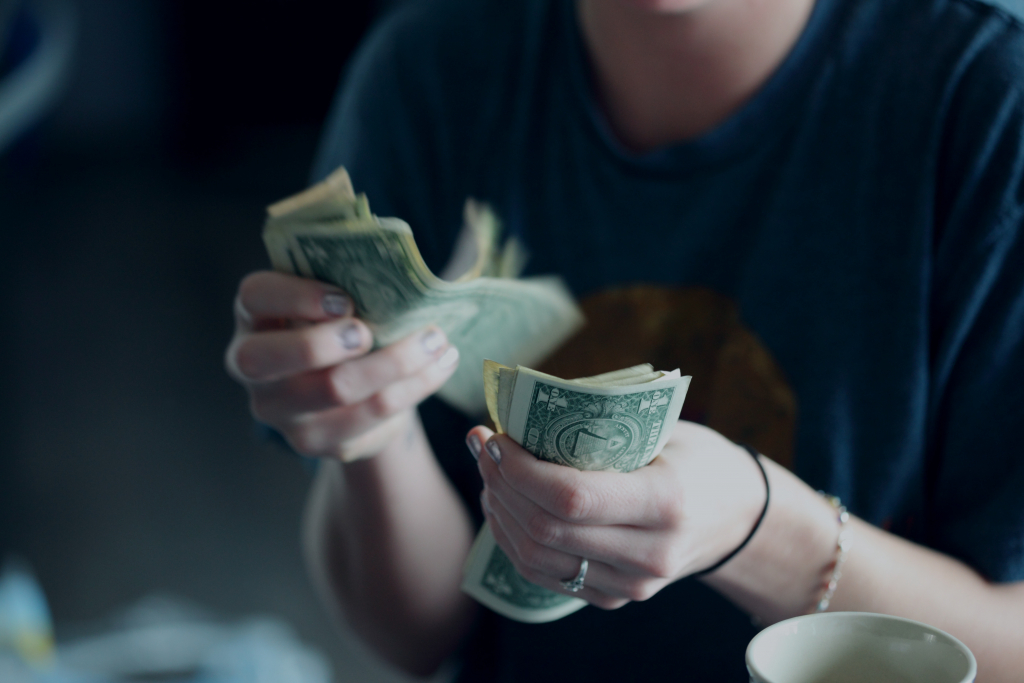 House Hacking image. Photo of woman counting dollar bills.