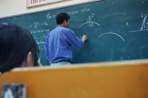 Male teacher writing on chalkboard