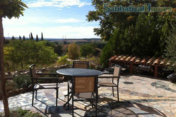 Image of an outdoor stone patio with a table overlooking the Spanish countryside. 