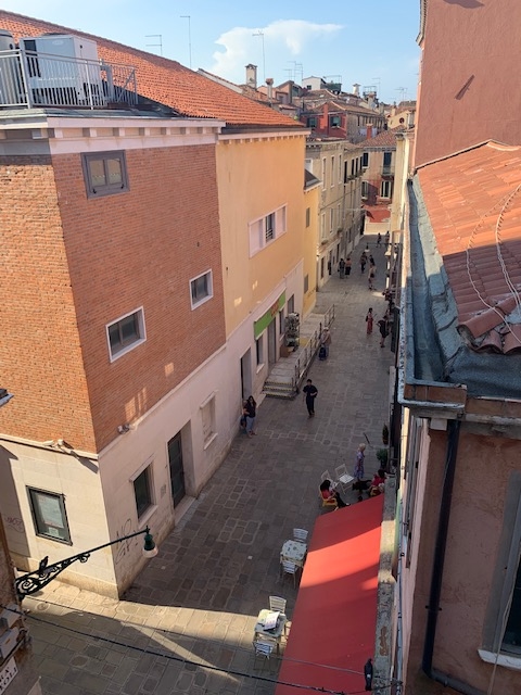 View of a Venice, Italy street with shops and a café from an apartment.