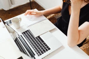 Person typing on a computer and taking notes.