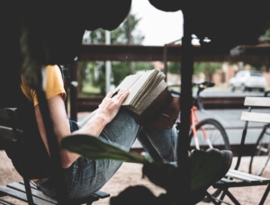 Person sitting outside near a bike reading scaled