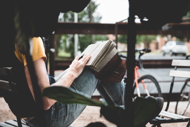 Person sitting outside near a bike reading scaled